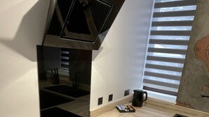 Une cuisine moderne dotée d’une plaque de cuisson à induction noire, d’un four encastré et d’une fenêtre avec des stores.
