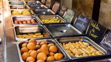 A buffet with various food items in metal containers, including what appears to be croissants and other pastries.