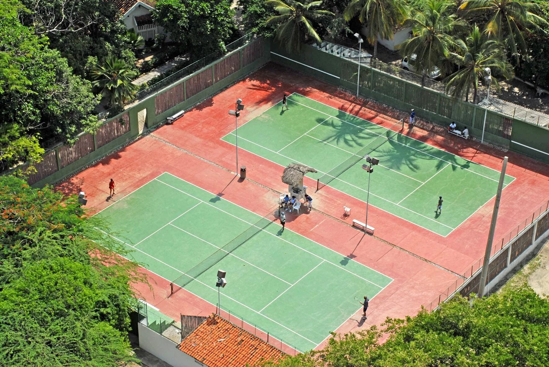 An outdoor tennis court surrounded by trees and a fence.