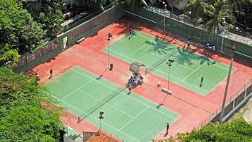 An outdoor tennis court surrounded by trees and a fence.