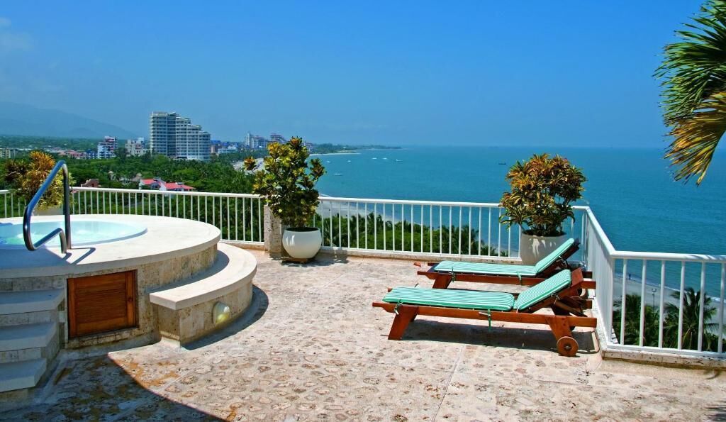 Une terrasse sur le toit avec une piscine, des chaises longues et des plantes en pot.