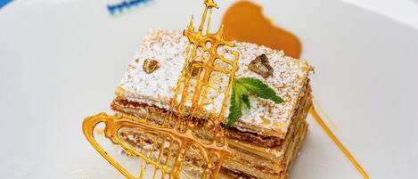Un postre con un hilo dorado y una hoja de menta sobre un plato blanco.