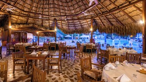A restaurant with thatched roof, wooden tables, and chairs, with a view of a pool and outdoor seating. - Hotel Irotama XXI (Santa Marta)