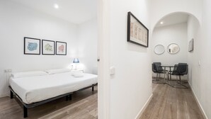 Ein Schlafzimmer mit einem Bett, einem Nachttisch mit Lampe und drei gerahmten Karten an der Wand.
