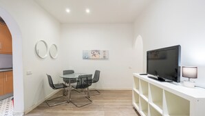 Eine moderne Küche mit Essbereich, einem Fernseher und einer Lampe.