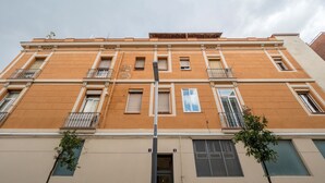 Ein mehrstöckiges Gebäude mit einer beigefarbenen Fassade, mehreren Balkonen und einem zentralen Eingang.