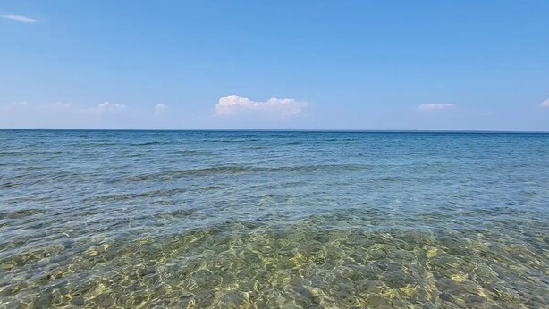 Una playa con aguas poco profundas y un mar tranquilo.