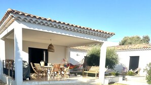 A poolside area with a covered patio, outdoor furniture, and a swimming pool.