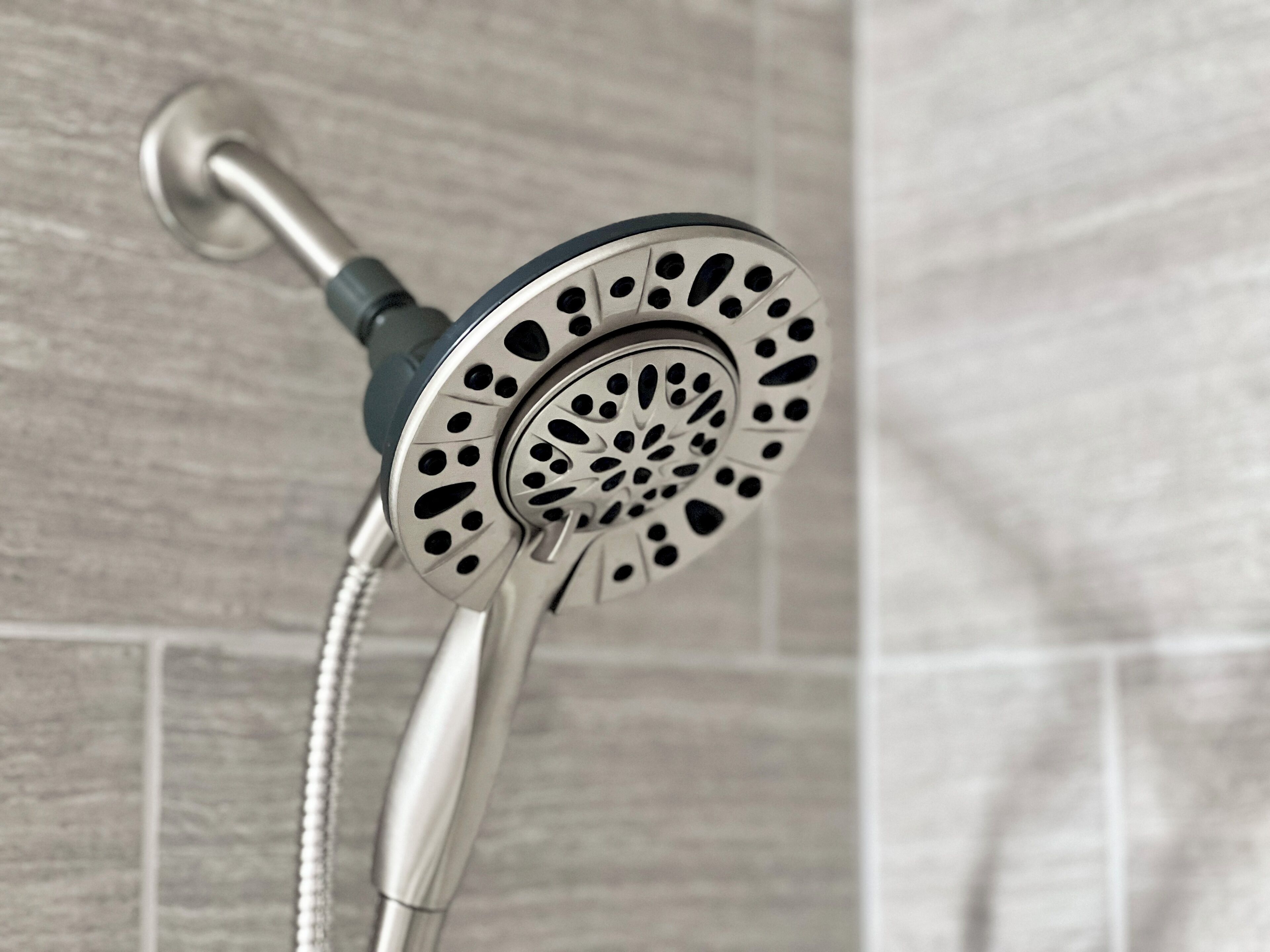 A showerhead with a perforated design, attached to a metal fixture.
