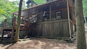 Een rustieke houten chalet met een balkon en een trap naar een hoger gelegen verdieping.