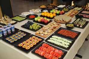 Un bufé con diversos alimentos, entre ellos frutas, verduras y pasteles.