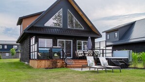 Une maison moderne dotée d’une grande terrasse, d’un espace salon extérieur et d’un garage apparent.