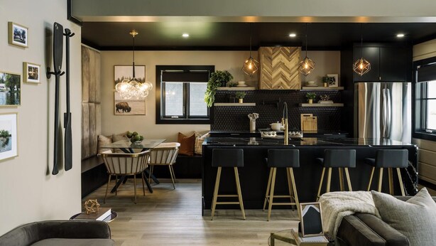 Une cuisine moderne dotée d’un îlot central, de tabourets de bar, de luminaires suspendus et d’un coin repas avec un canapé et des chaises.