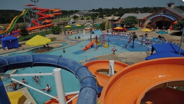 A water park with multiple slides and pools, including a large orange slide and a blue pool area. - Central! Minutes to Magnolia, Baylor University, Cameron Park  Zoo and more.  (Waco)