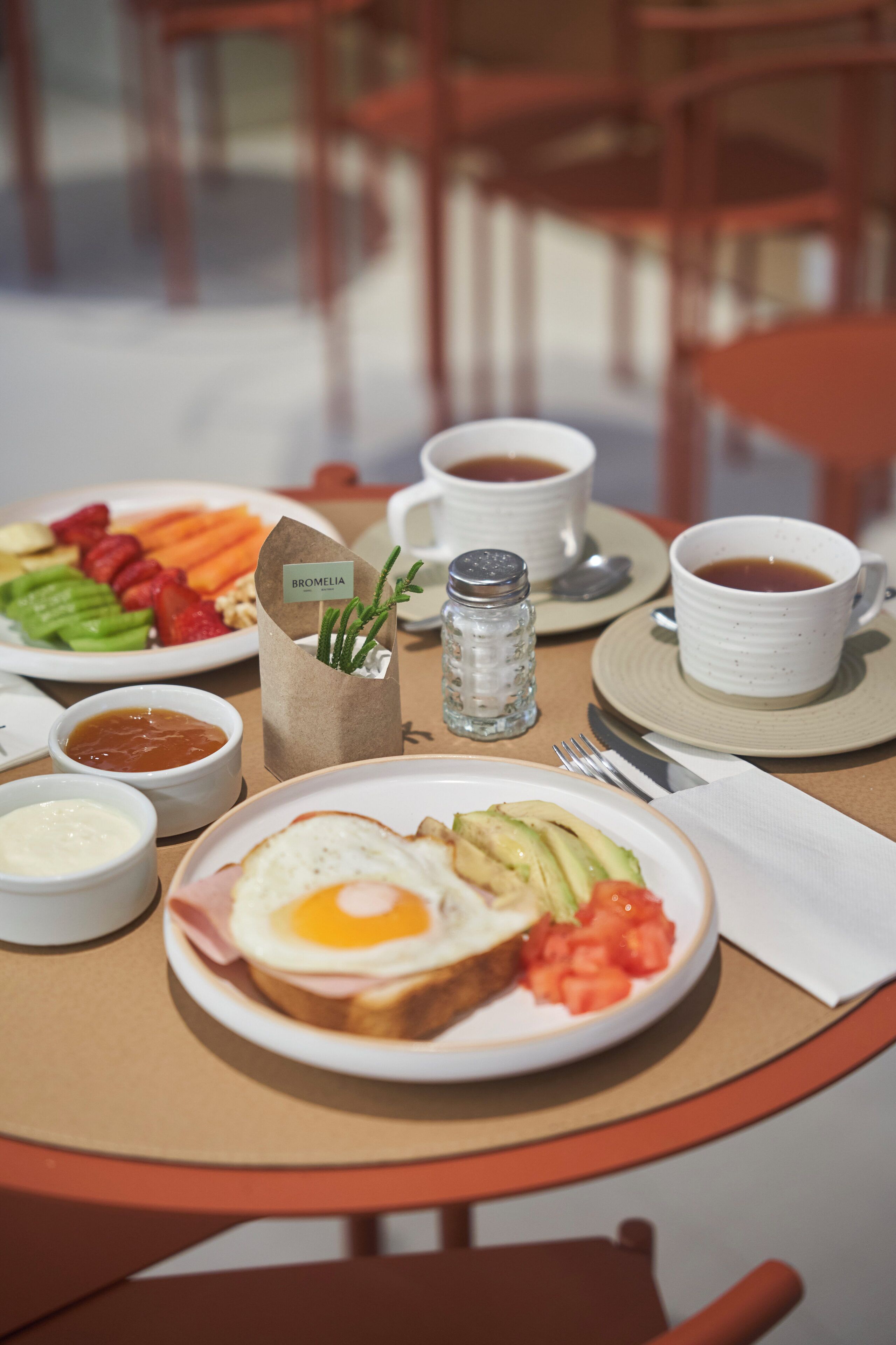 A breakfast table with plates of food, cups of coffee, and condiments.