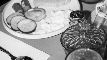 A dining table with a plate of food, a glass of water, and a salt shaker.