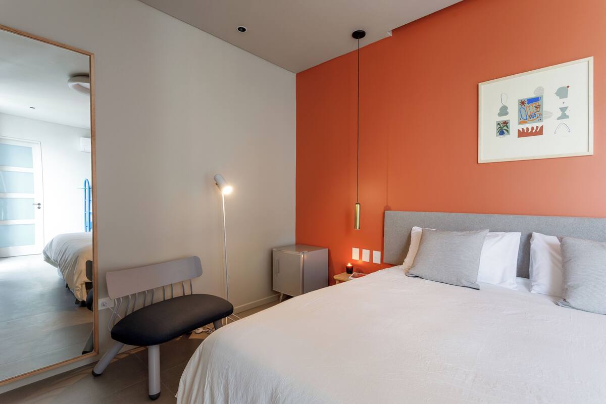 Une chambre d’hôtel avec un lit, une table de chevet, une lampe et un miroir.
