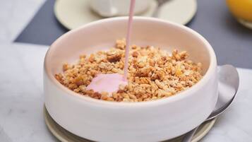 Un tazón de granola con un líquido rosado sirviéndose.