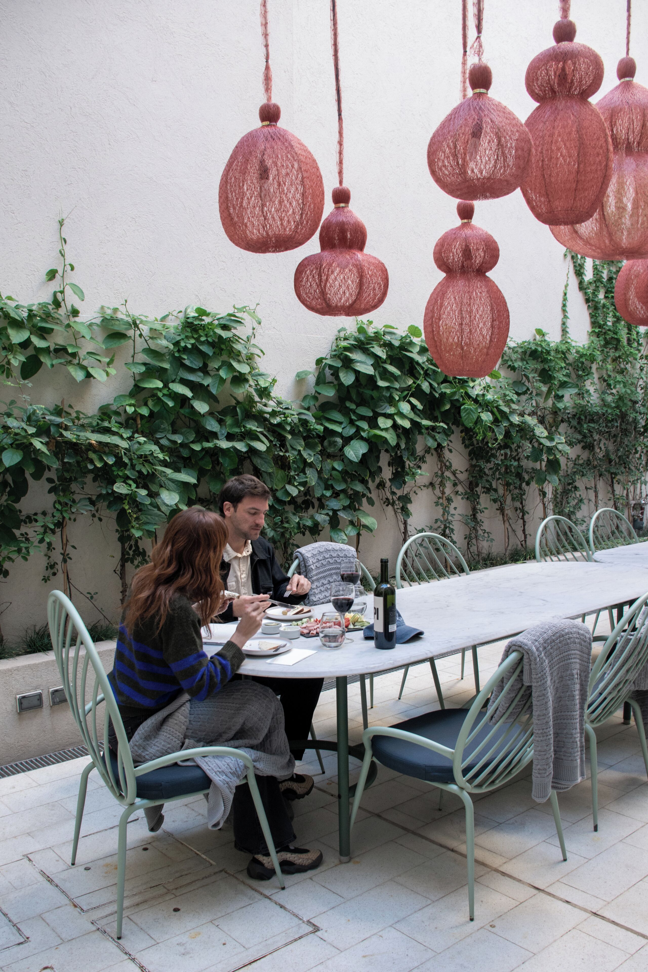 A dining table with chairs, a bottle of wine, and a plate of food.