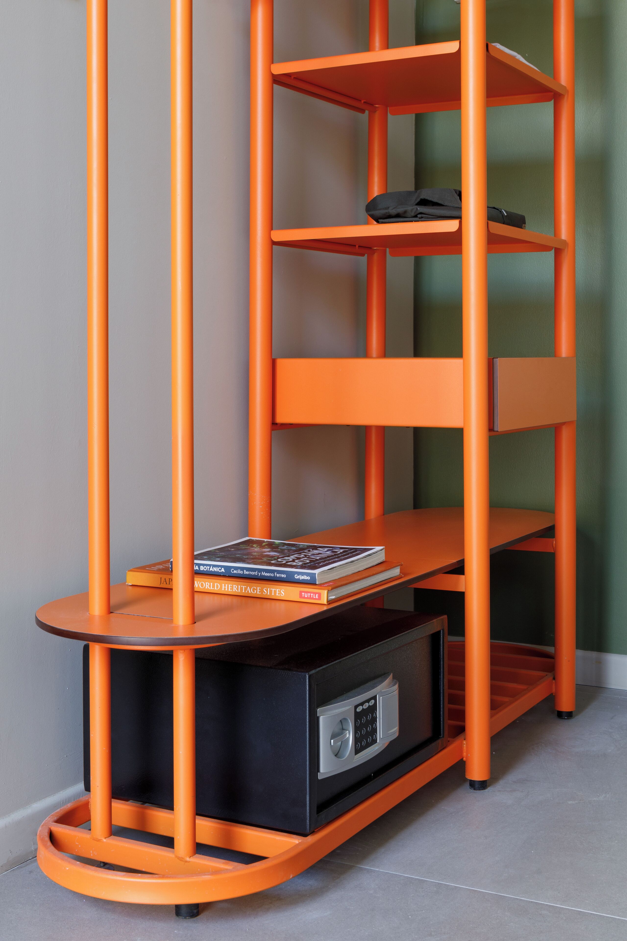 A corner bookshelf unit with a built-in radio, featuring a stack of books and a remote control.