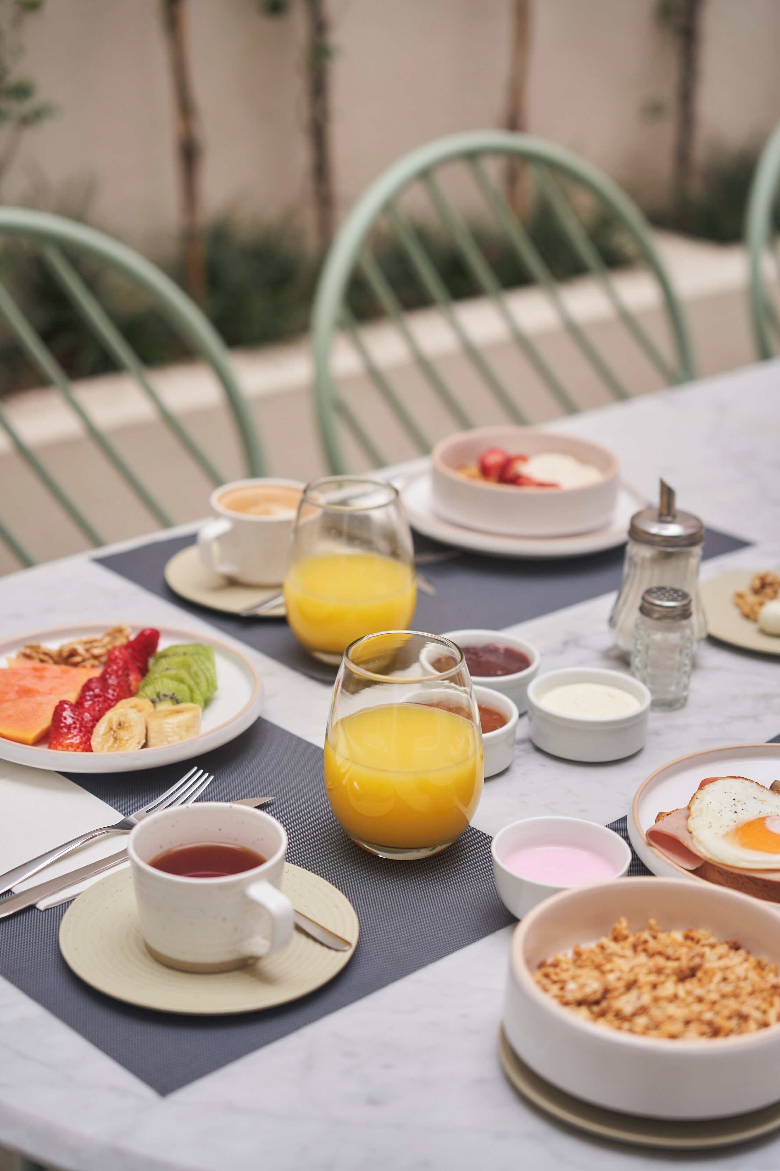 Una mesa de desayuno con platos de comida, un vaso de jugo de naranja y una taza de té.