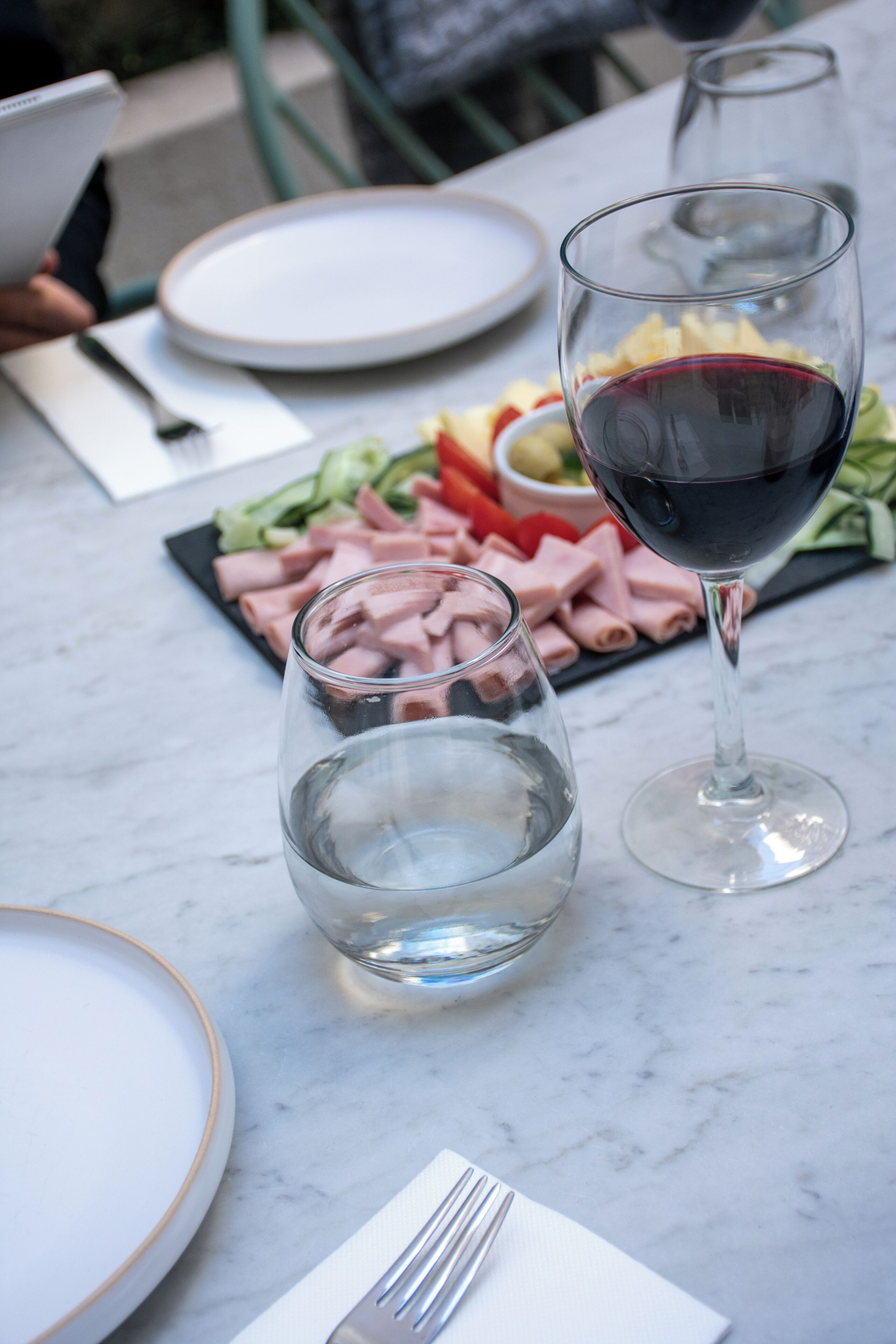 A table with plates, cutlery, a glass of red wine, and a glass of water.