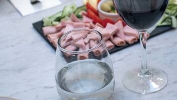 A table with plates, cutlery, a glass of red wine, and a glass of water.