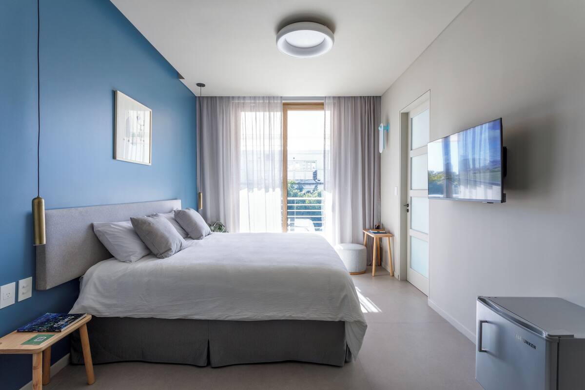 Une chambre d’hôtel moderne dotée d’un grand lit, d’une télévision à écran plat et d’une petite kitchenette.