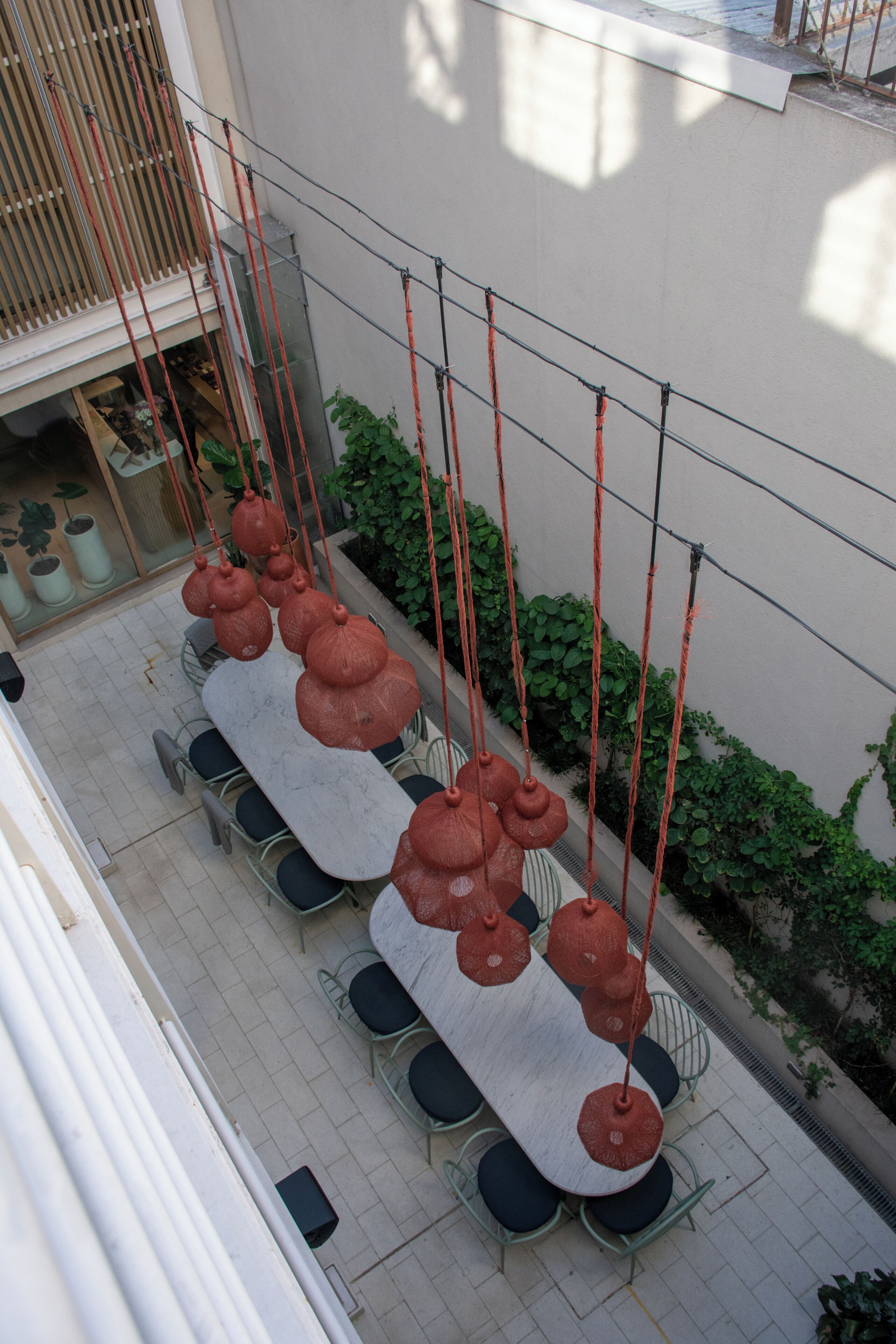 A dining area with a long table, chairs, hanging red lanterns, and a view of the building's interior.