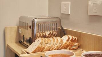 Ein Frühstücksbuffet mit Brot, Marmelade und einem Toaster.