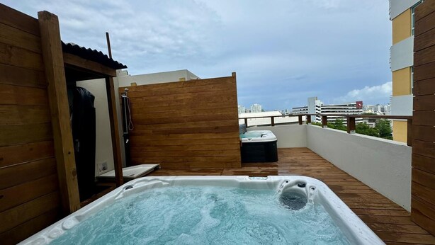 En takterrass med ett bubbelbad, ett trädäck och utsikt över stadsbilden.