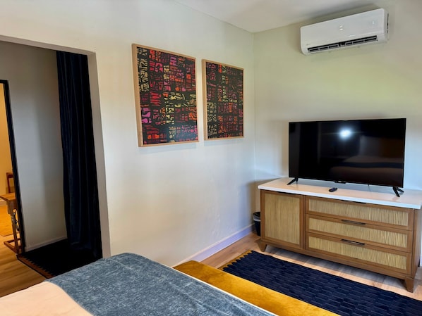 A hotel room with a bed, a TV, a wooden dresser, and two abstract paintings on the wall. - Metro Art Hotel (San Juan)