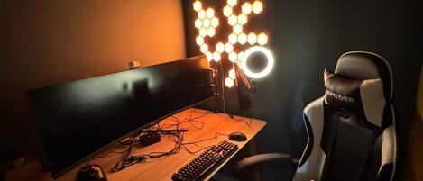 Una silla de juegos, un escritorio con teclado y ratón, y un monitor.