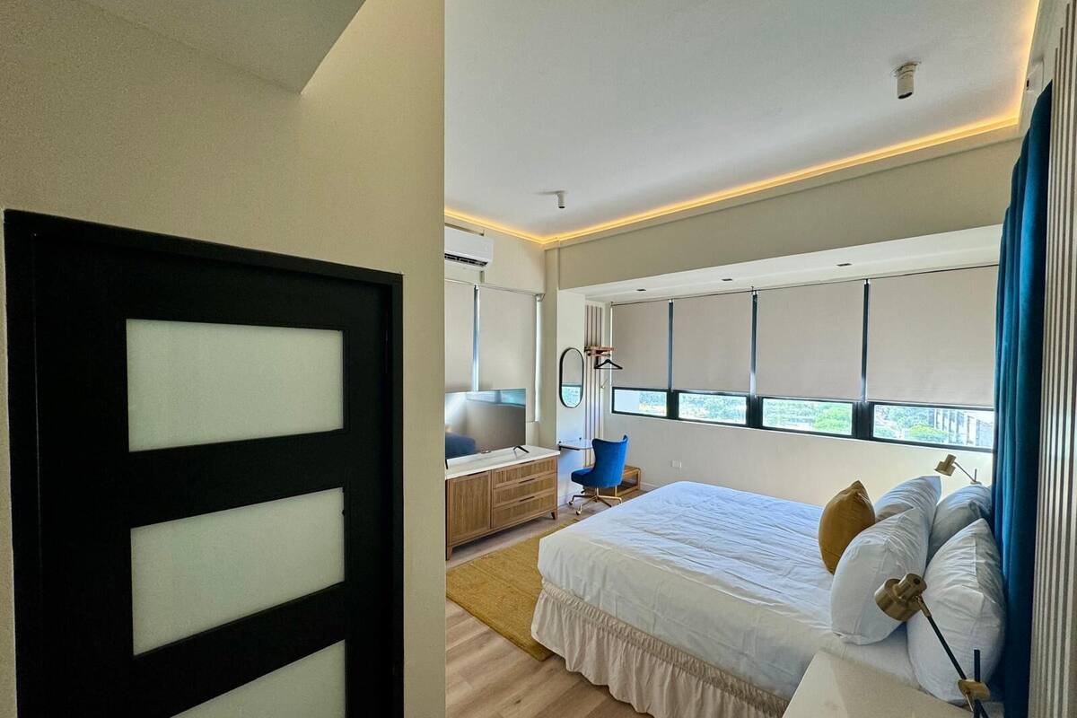 Een moderne slaapkamer met een groot bed, een nachtkastje, een stoel en een raam met zonwering.
