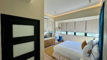 Un dormitorio moderno con una cama grande, una mesita de noche, una silla y una ventana con persianas.
