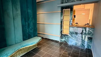 A modern interior with a bench, tiled floor, and a marble wall.