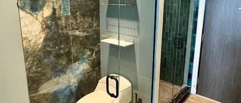 A modern bathroom with a toilet, a glass shower enclosure, and a wooden floor.