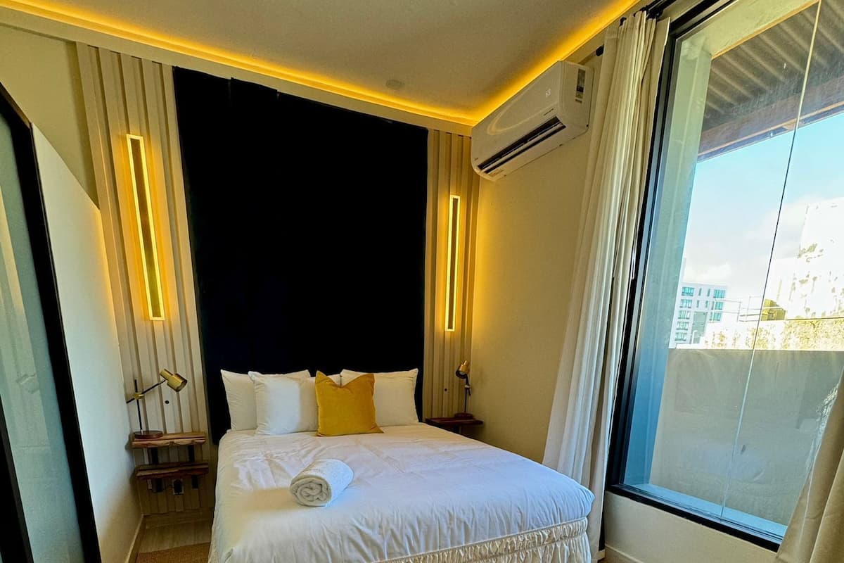 Een hotelkamer met een groot bed, een raam met uitzicht en een luchtverwarmer aan het plafond.