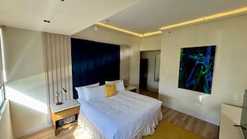Een moderne slaapkamer met een groot bed, nachtkastje, spiegel en wanddecoratie.