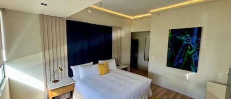 Een moderne slaapkamer met een groot bed, nachtkastje, spiegel en wanddecoratie.