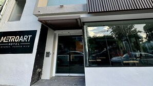 Ett modernt hotell med en entré av glas och en skylt med texten ”METROART HOTEL Antarte, Puerto Rico”.