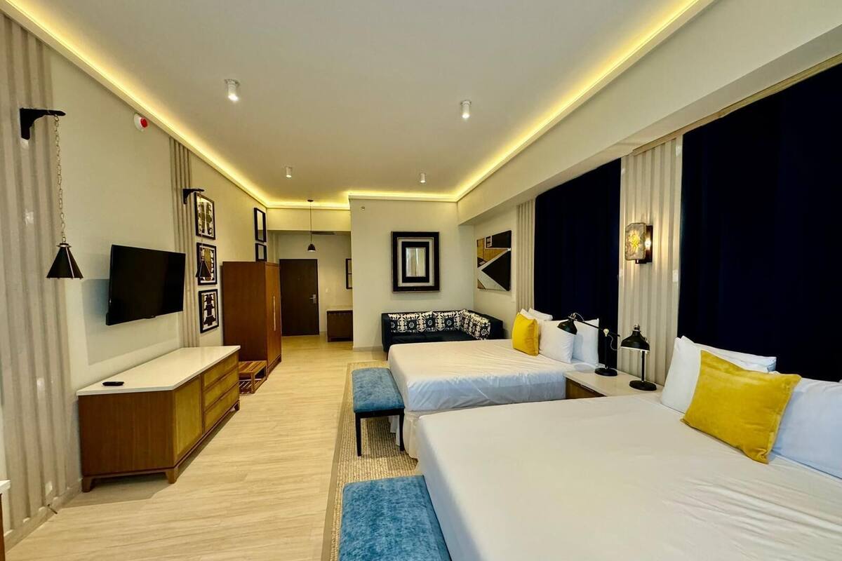 Een moderne hotelkamer met twee bedden, een televisie, een kledingkast en een bureau.