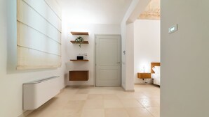 A hallway with a white door, a small plant, and a bedside table with a lamp.