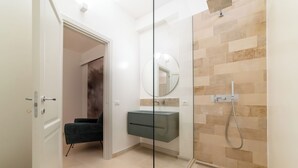 A modern bathroom with a glass shower enclosure, a built-in sink, and a mirror.