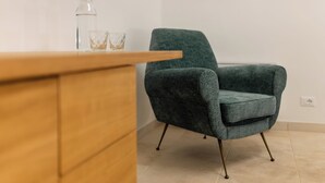 A modern room with a wooden desk, a green armchair, and a bottle of water.