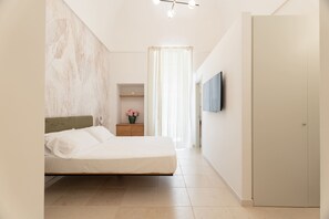 A bedroom with a bed, a nightstand, a TV, and a door.