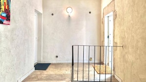 A narrow hallway with a concrete floor, a metal railing, and a door at the end.