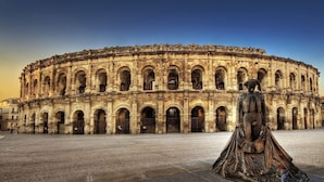A historic building with a circular facade and a statue in the foreground.