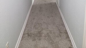 A narrow hallway with a carpeted floor, white walls, and a wooden door at the end. - Cute And Cozy Hostel (Houston)