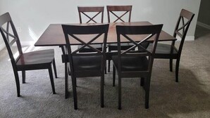 A dining area with a rectangular table and six chairs with cross-back designs. - Cute And Cozy Hostel (Houston)